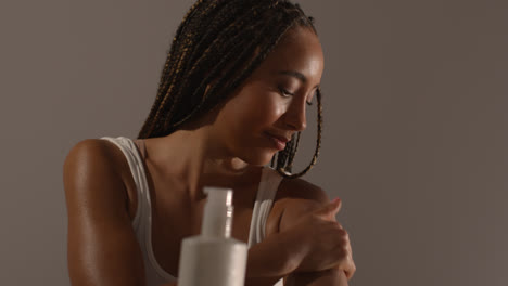 Studio-Skincare-Beauty-Shot-Of-Young-Woman-With-Long-Braided-Hair-Putting-Moisturiser-Onto-Arm-And-Shoulder-1